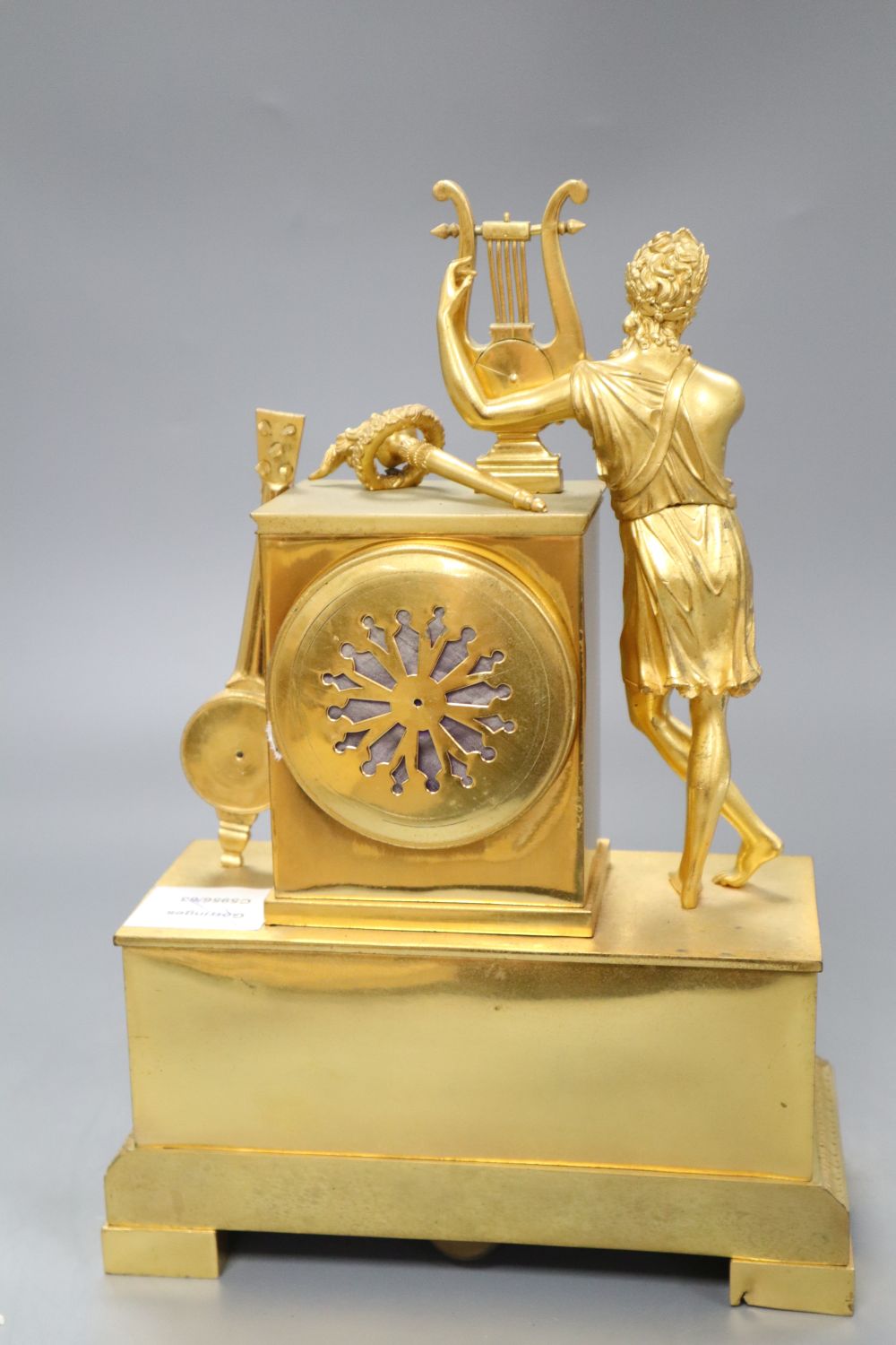 A French Empire design ormolu eight day mantel clock, the case surmounted with a Grecian figure playing a lyre, height 31cm